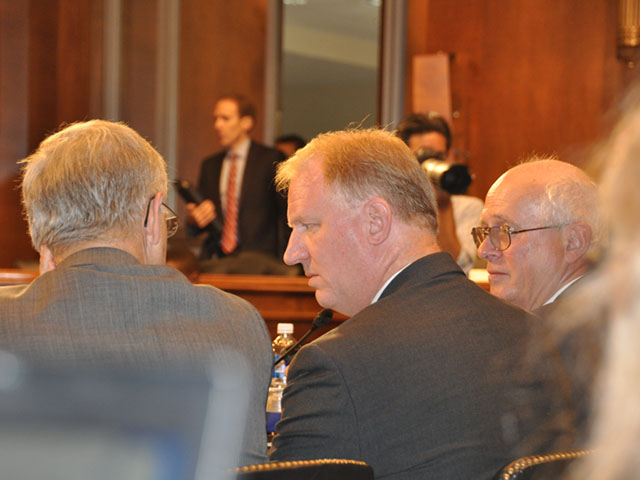 Roger Johnson of the NFU, Chris Novak of the NCGA and Bob Young of Farm Bureau talk in their cramped quarters in front of the Senate Judiciary committee during a hearing on ag consolidation. (Photo by Emily Unglesbee)