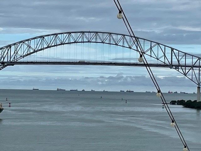 Pictured is the Bridge of the Americas, a road bridge in Panama spanning the Pacific entrance to the Panama Canal, and beyond that, ships anchored and waiting to pass through. (Photo by Rosemary Acker Radant)