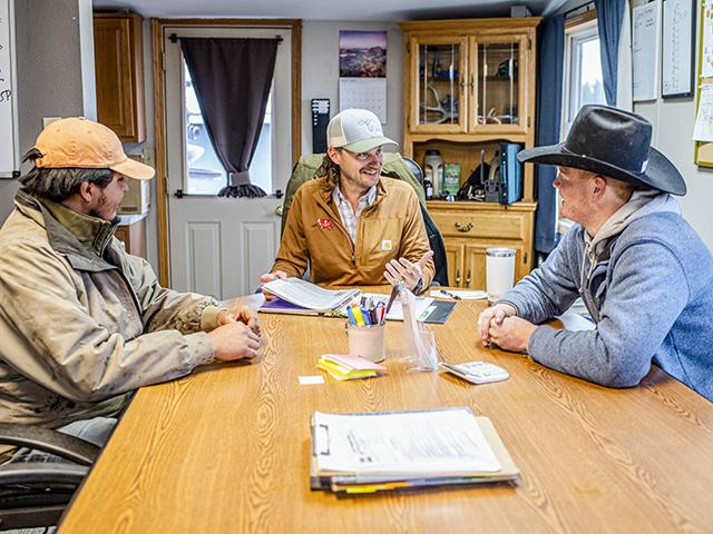 Logan Pribbeno goes over paperwork with employees on his fifth-generation family ranch, Wine Glass Ranch, near Imperial, Nebraska. He adopted a laid-back, West Coast management style in hiring and retaining workers for the ranch. (Evan Semon)