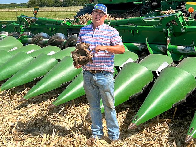 Jerry Workman is holding a vintage 1903 corn sheller in front of a modern John Deere S680 combine. (Steve Thompson)