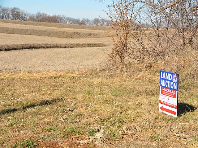 A land auction sign from last year in southwest Iowa. Farmland values over the past three years have outperformed the stock market, but a pair of former Kansas City Federal Reserve presidents caution the national debt and monetary policy could cause a future devaluation. (DTN photo by Chris Clayton)