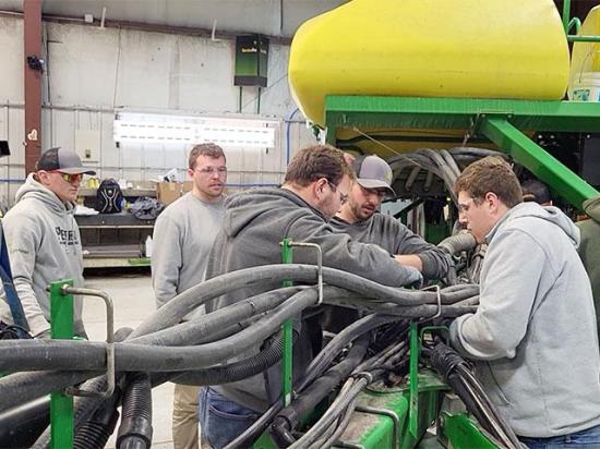 Jacob Parr (second from left) instructs Iowa State University Ag 450 Farm students on how to repair a piece of machinery. (Photo courtesy of Iowa State University)