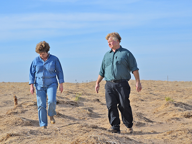 Jillane Hixson and her brother Ron walk through a windblown field where drought has turned the soil to powder. (Progressive Farmer photo by Russ Baldwin)