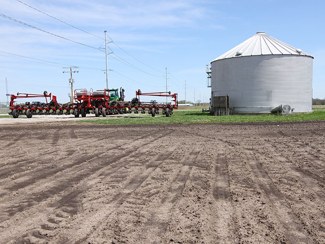 A planter sits awaiting its turn next to a field in central Illinois. Cool and rainy conditions have kept many farmers out of the fields and pushed corn planting progress behind its average pace. (DTN photo by Pamela Smith)