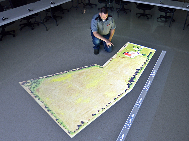 Asmark&#039;s KJ Johnson studies a field map projected on the floor. Students learn strategies for approaching each field. (DTN/Progressive Farmer photo by Jim Patrico)