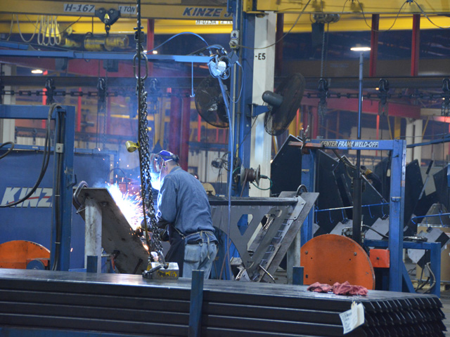 A welder at Kinze Manufacturing in Williamsburg, Iowa, works on grain carts as the company prepares for summer and fall deliveries. Kinze uses a significant amount of steel daily, and tariffs on steel imports have driven up prices dramatically. Tariffs on farm products also affect Kinze&#039;s farmer customers. (Photo by Chris Clayton) 