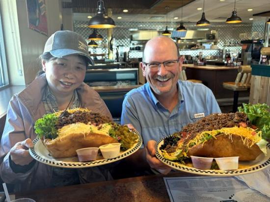 Cindy Li with Bimbo Bakeries USA and DTN Crops Editor Jason Jenkins attempted to tackle the "Wow! Taco Salad" for lunch at the Black Bear Diner in Garden City, Kansas, during Day 2 of the 2025 Hard Winter Wheat Tour. (Photo courtesy of Tyllor Ledford)