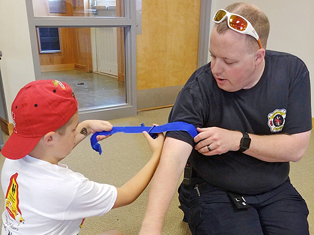An emergency responder shows a Progressive Agriculture Safety Day attendee a bleeding-control technique. (Progressive Farmer image by Progressive Agriculture Foundation)