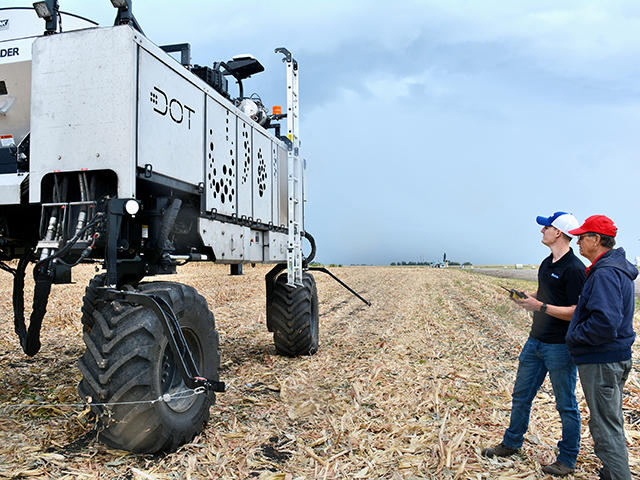 Kyle Mensen, of Raven Autonomy, shows Dick Isaacson how to maneuver Dot with a remote control. (Progressive Farmer image by Matthew Wilde)