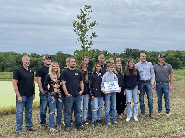 The Schleisman family, on the left, celebrate earning the Wergin Good Farm Neighbor Award with Iowa Secretary of Agriculture Mike Naig, second on the right, and Alex Frazier of Frazier Nursery, on the far right, who presented the family with a bur oak tree. (DTN photo by Susan Payne)