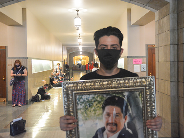 At the Nebraska Capitol on Thursday, Christian Munoz holds a portrait of his father, Rogelio Munoz Calderon, who died of COVID-19 in May at the age of 52. (DTN photo by Chris Clayton) 