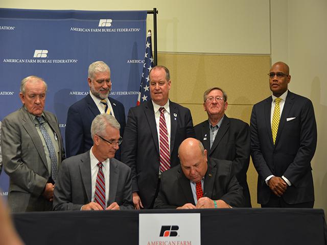 Zippy Duvall, president of the American Farm Bureau Federation, signs a memorandum of understanding (MOU) with David Gilmore, senior vice president for sales and marketing in Ag &amp; Turf at Deere, on Jan. 8 at the AFBF annual meeting in San Juan, Puerto Rico. Standing are FB state presidents Tom McCall of Georgia, Mark McHargue of Nebraska, Jamie Johansson of California, Richard Wilkins of Delaware and Collis Jones, vice president of U.S. policy and strategy at John Deere. (DTN photo by Chris Clayton)