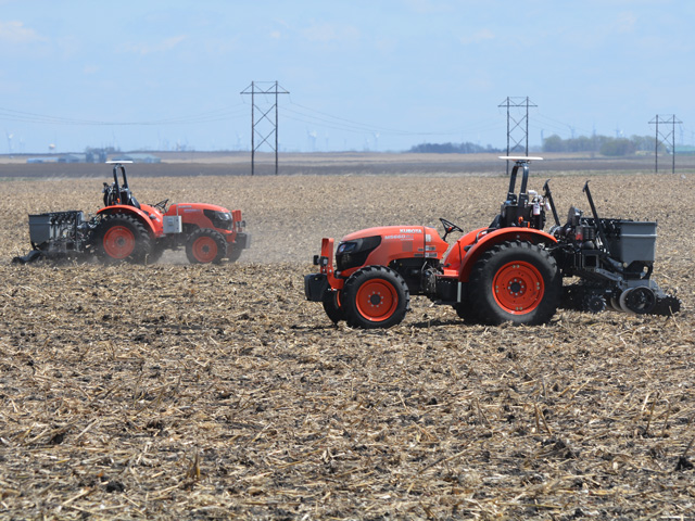 A remote-controlled Kubota M5660SU tractor plants soybeans last week at Bellcock Farms near Sac City, Iowa, while another identical unit heads to the seed tender for a refill. Sabanto, an autonomous technology company, is seeding soybeans in Iowa and Illinois this spring. (Progressive Farmer photo by Matthew Wilde)