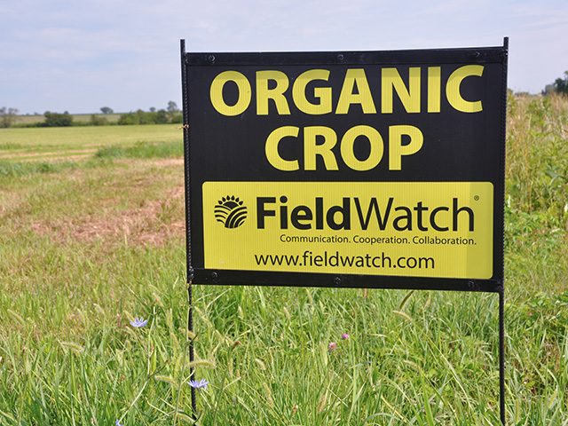 A FieldWatch sign blares its bright yellow warning near an organic field in southeast Nebraska. The company hopes to expand to serve all kinds of sensitive fields, including herbicide-tolerant row crops. (DTN photo by Emily Unglesbee) 