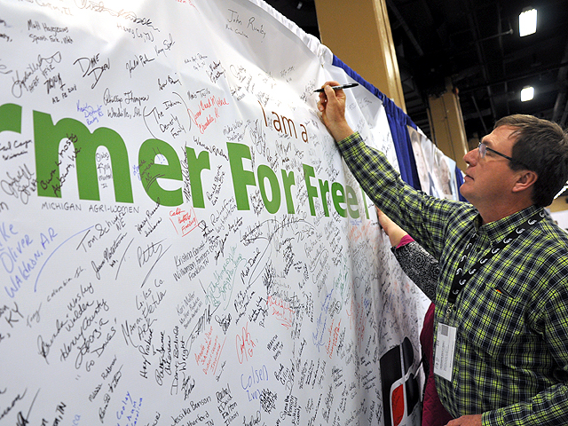 A Montana farmer in January 2018 signs a Farmers for Free Trade sign at the American Farm Bureau Federation annual meeting. DTN's Urban Lehner says farmers shouldn't go overboard with enthusiasm over trade deals with Japan and China. (DTN file photo by Chris Clayton)