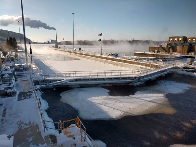 In spite of the extreme cold temperatures, preventive maintenance still needs to be done by the St. Paul District U.S. Army Corps of Engineers (USACE) during the winter months. At Lock and Dam 4, an USACE staff of four regularly flushes fast-forming ice out of the chamber to keep the miter gates and valves from freezing up. A contractor barge utilizes a bubbler to keep from freezing in place. (Photo courtesy USACE St. Paul District, Mississippi Valley Division)