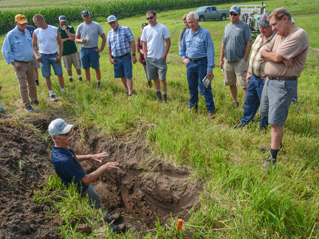 Mike Petersen, an agronomist with Orthman Manufacturing, stands in a soil pit on Grant and Tana Guetzko&#039;s farm near Delhi, Iowa. He and a colleague dug the pit as part of a soil health field day to show the Guetzkos and attendees how soil structure is affected by crop production practices. (DTN photo by Matthew Wilde)