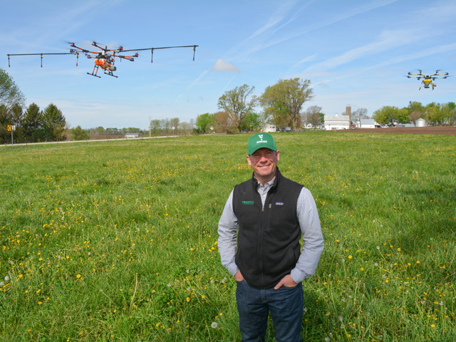Two drones hover behind Michael Ott, CEO of Rantizo, at the company&#039;s proving grounds near Iowa City, Iowa, during an early May media day. Rantizo showed its latest drone spraying and seeding technology and equipment. (DTN photo by Matthew Wilde)